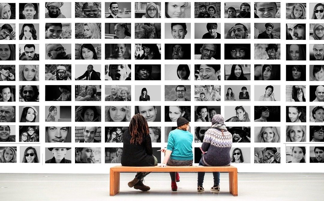 three people sitting in front of large artwork